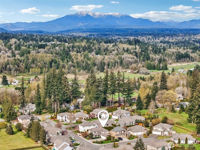 aerial perspective of suburban area featuring a mountainous background and a heavily wooded area