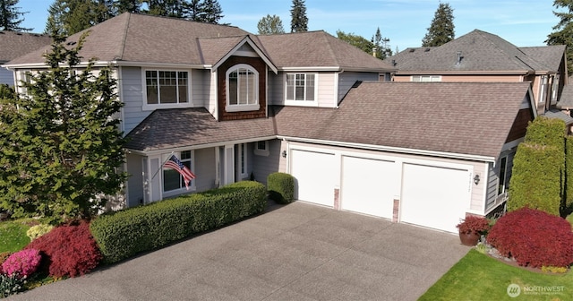 view of front facade with concrete driveway, a garage, and roof with shingles