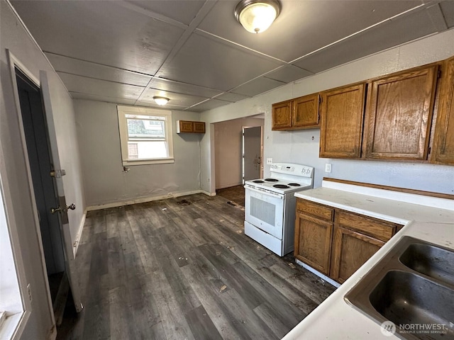 kitchen with white electric stove, brown cabinetry, dark wood-type flooring, light countertops, and a sink