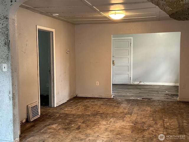 empty room featuring visible vents, arched walkways, and wood finished floors