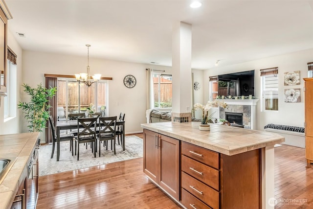 kitchen with tile counters, visible vents, open floor plan, and light wood finished floors