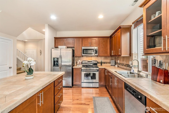 kitchen featuring visible vents, tile counters, light wood-style flooring, appliances with stainless steel finishes, and a sink