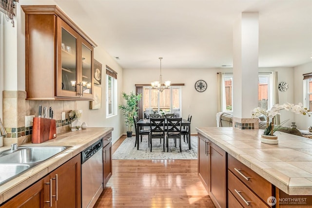 kitchen featuring brown cabinets, dishwasher, and tile counters