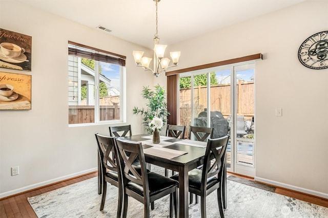 dining area featuring a notable chandelier, a healthy amount of sunlight, baseboards, and wood-type flooring