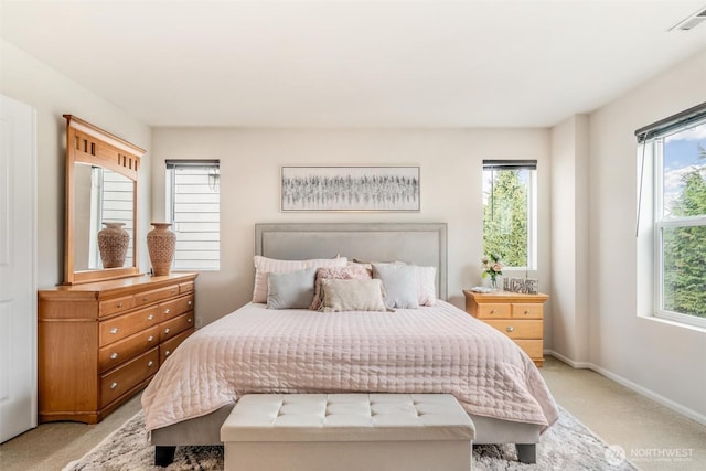 bedroom featuring multiple windows, light colored carpet, visible vents, and baseboards