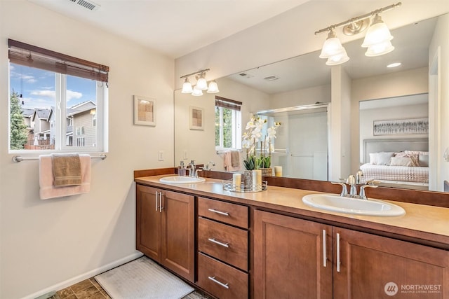 bathroom with a shower stall, double vanity, ensuite bathroom, and a sink