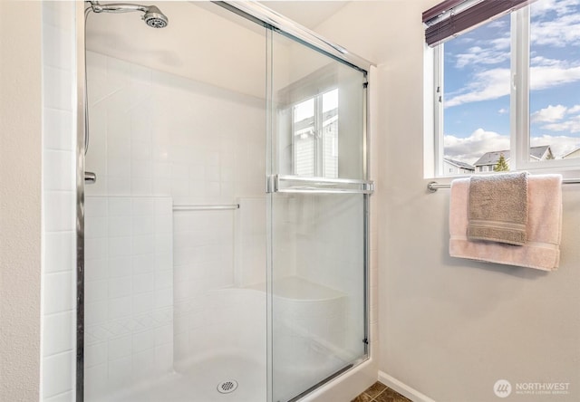 bathroom featuring a shower stall and baseboards