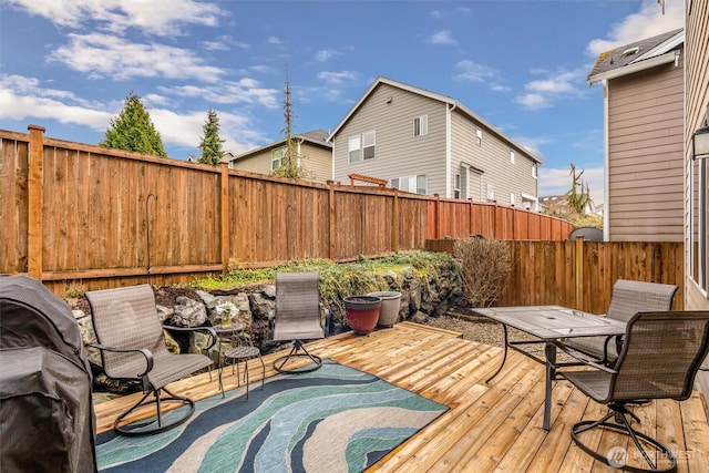 wooden deck featuring a fenced backyard and a grill