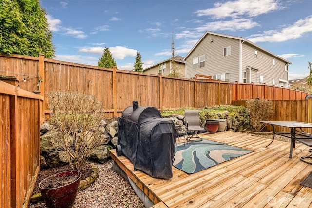 wooden deck with area for grilling and a fenced backyard