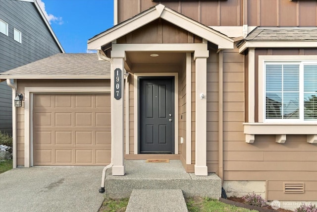 doorway to property featuring an attached garage, board and batten siding, and roof with shingles