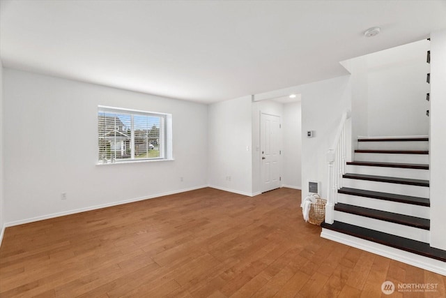 unfurnished living room featuring visible vents, stairs, baseboards, and hardwood / wood-style floors