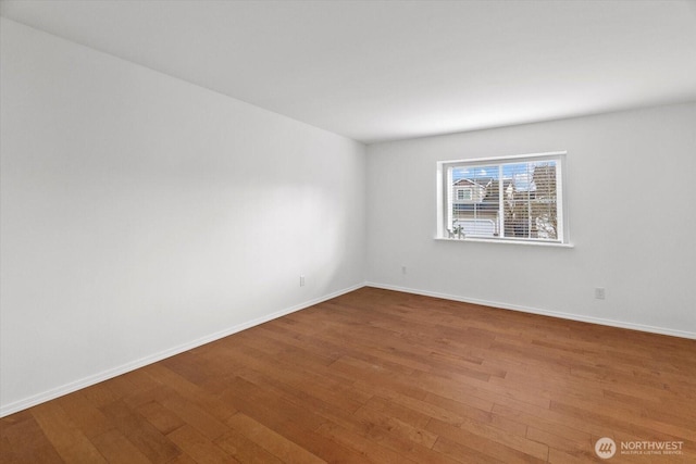 spare room with baseboards and hardwood / wood-style floors