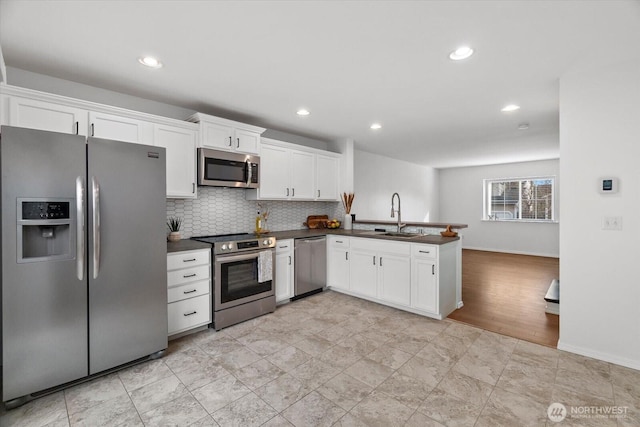 kitchen featuring a sink, dark countertops, white cabinets, and stainless steel appliances