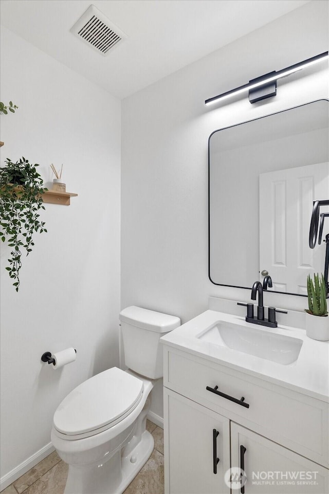 half bathroom with visible vents, baseboards, toilet, tile patterned floors, and vanity