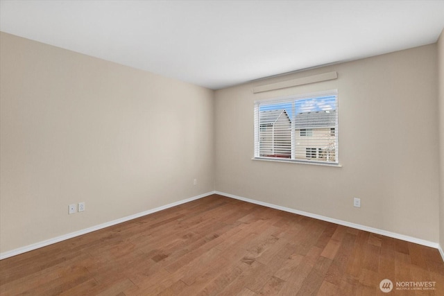 spare room with baseboards and wood finished floors