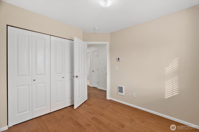 unfurnished bedroom with light wood-style flooring, visible vents, baseboards, and a closet