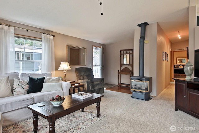 living area with light carpet, a wood stove, and vaulted ceiling