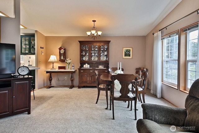 dining room with lofted ceiling, carpet, baseboards, and a chandelier