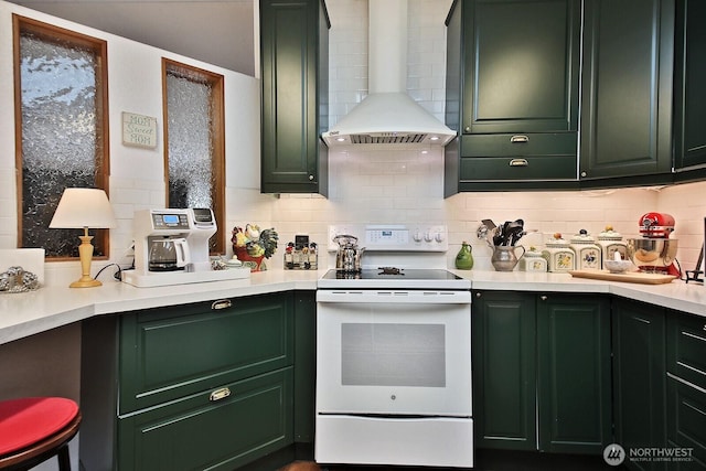 kitchen with green cabinets, backsplash, white range with electric stovetop, and wall chimney range hood