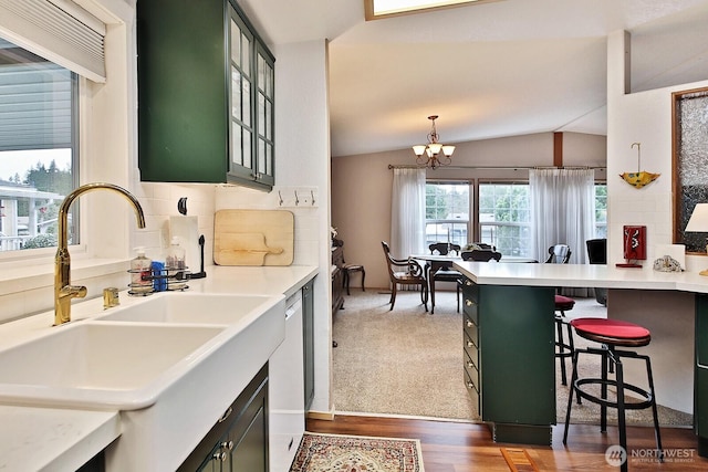 kitchen featuring a kitchen bar, a sink, light countertops, green cabinetry, and lofted ceiling