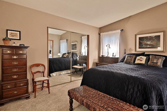 bedroom featuring a closet, lofted ceiling, and light colored carpet