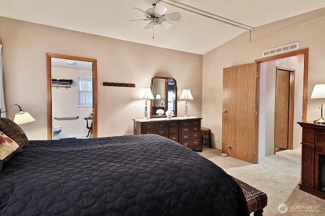 carpeted bedroom featuring visible vents, ensuite bath, and vaulted ceiling