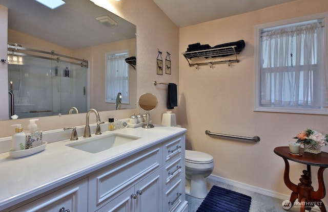 full bath featuring baseboards, a shower stall, vanity, and toilet