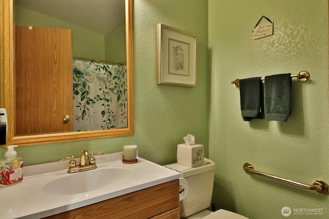 bathroom featuring toilet, vanity, a shower with shower curtain, and a textured wall