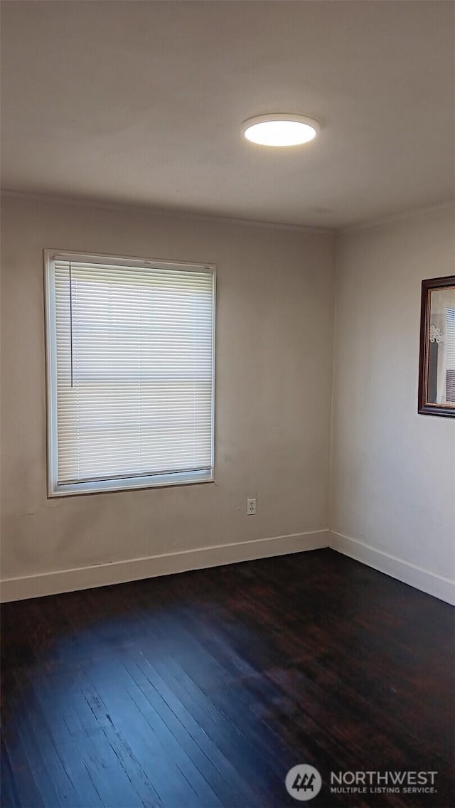 spare room with dark wood finished floors and baseboards