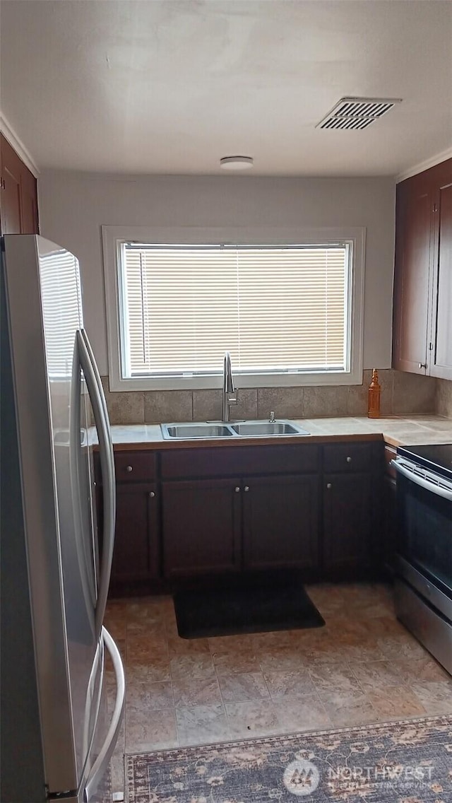 kitchen with visible vents, a sink, stainless steel appliances, dark brown cabinetry, and light countertops