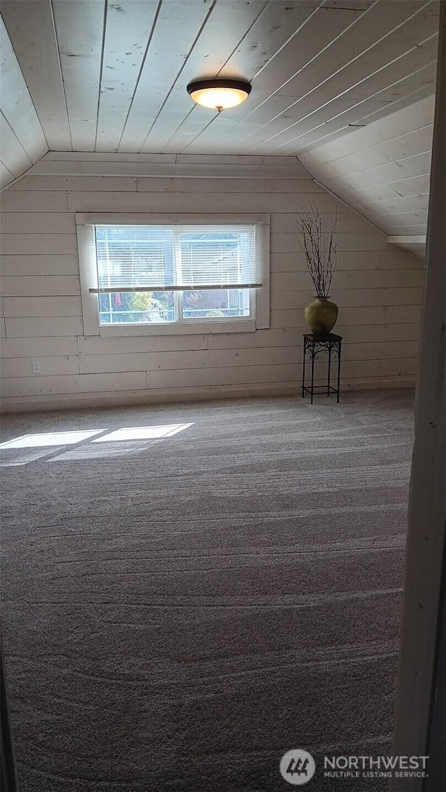 bonus room with vaulted ceiling, wood walls, and carpet floors