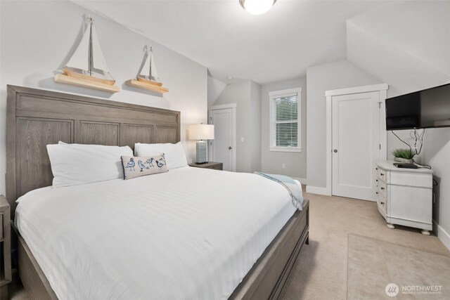 bedroom with lofted ceiling, baseboards, and light colored carpet