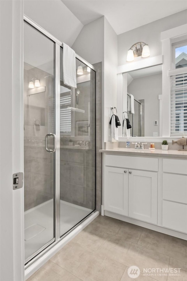 bathroom featuring vaulted ceiling, a shower stall, and vanity