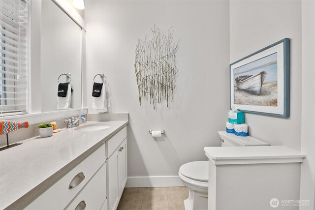 bathroom featuring toilet, tile patterned flooring, baseboards, and vanity