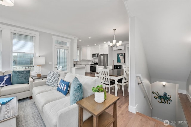 living area featuring light wood finished floors, baseboards, crown molding, a chandelier, and recessed lighting