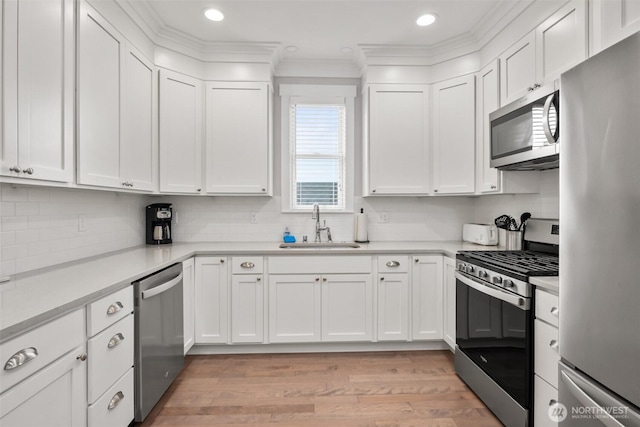 kitchen featuring white cabinetry, stainless steel appliances, a sink, and light countertops