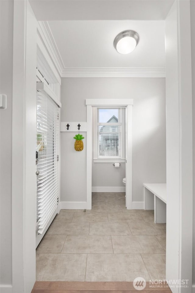 mudroom featuring crown molding, baseboards, and light tile patterned floors