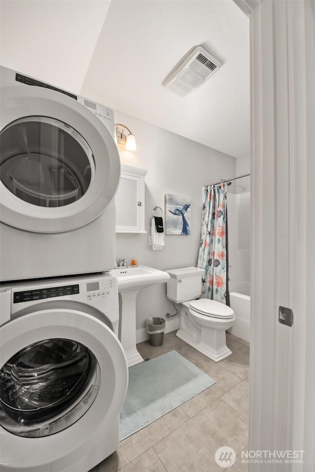 full bathroom featuring stacked washer and clothes dryer, visible vents, toilet, a sink, and tile patterned flooring