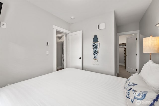 bedroom with stacked washer / drying machine, visible vents, a spacious closet, and carpet flooring