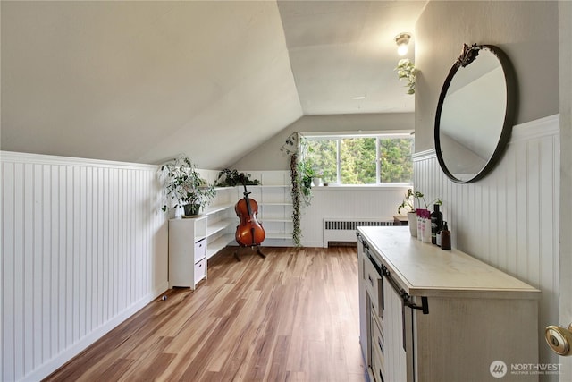 interior space featuring lofted ceiling, radiator, and light wood-style floors