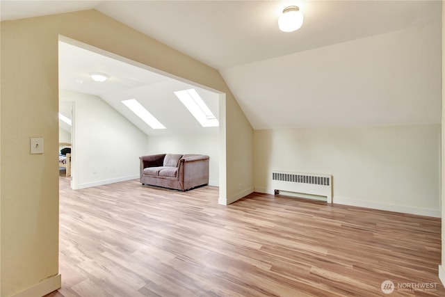 bonus room featuring baseboards, lofted ceiling with skylight, radiator, and light wood-style flooring