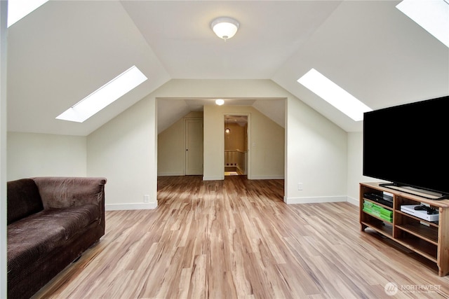 additional living space with baseboards, vaulted ceiling with skylight, and light wood-style flooring