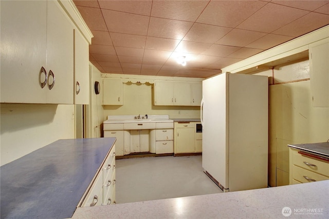 kitchen with stainless steel countertops, freestanding refrigerator, and a sink