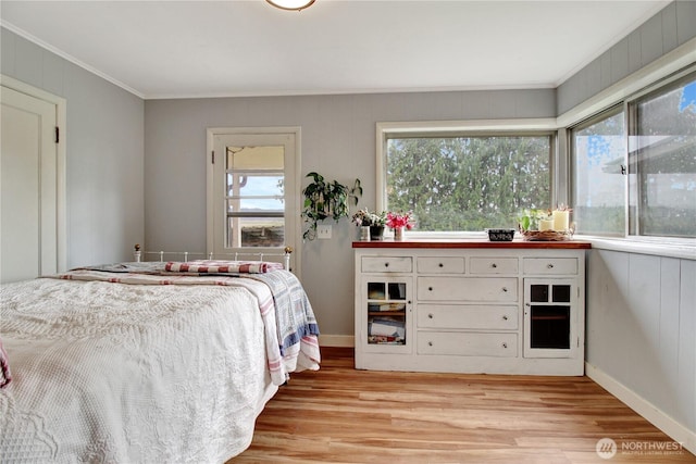 bedroom with light wood-type flooring, baseboards, and crown molding