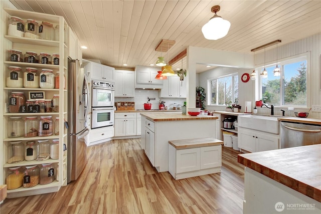 kitchen with a sink, wooden ceiling, appliances with stainless steel finishes, and wood counters