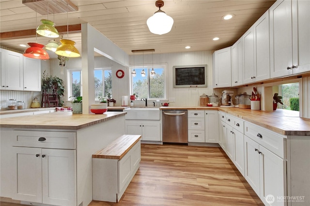 kitchen with dishwasher, white cabinets, a sink, and wood counters