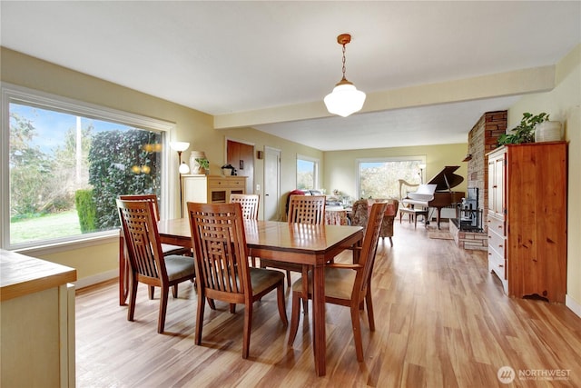 dining room with light wood-style flooring, beamed ceiling, and baseboards