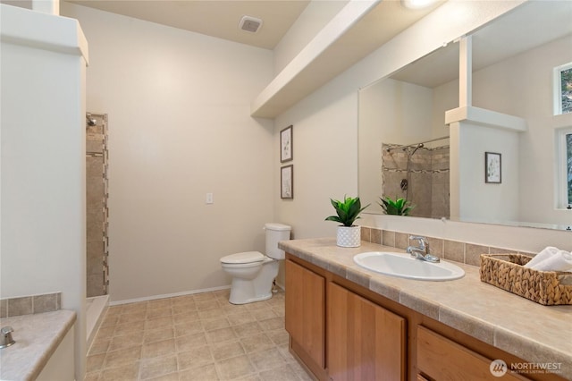 full bath with visible vents, baseboards, toilet, tiled shower, and vanity