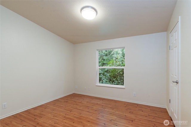 spare room with baseboards and light wood finished floors