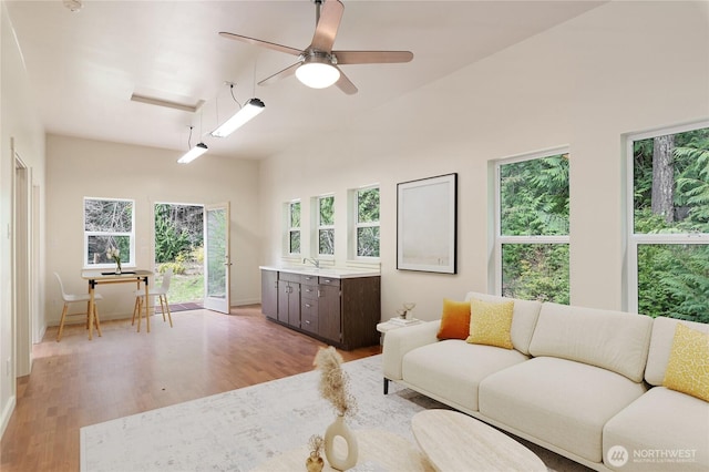 living room with light wood-type flooring, baseboards, and a ceiling fan